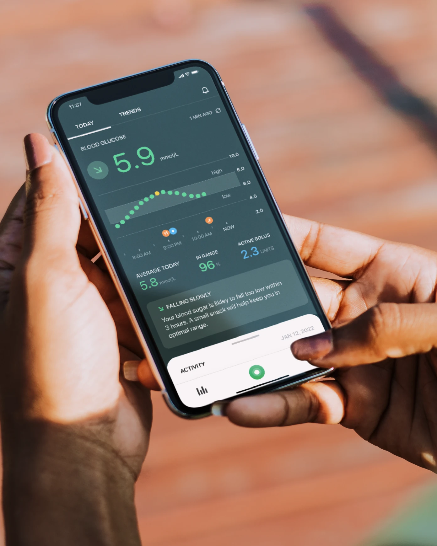 A person holding a phone with the Gluca glucose tracking app open.